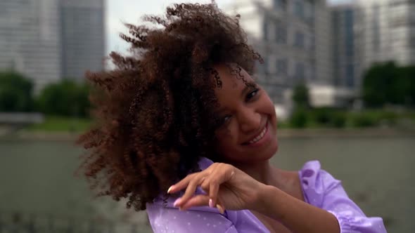Portrait of a Young Attractive African-American Woman with Curly Hair Dancing and Looking at the