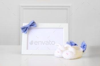 checkered bow tie and knitted baby booties at light grey background. Copy space. Newborn baby boy concept.