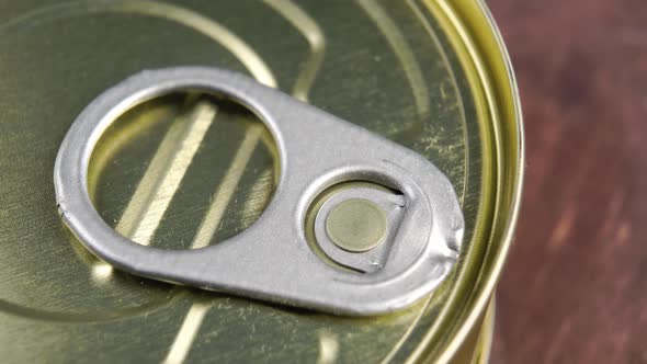 Conserved food aluminium can with pull ring on a wooden background. Unopened hermetic container