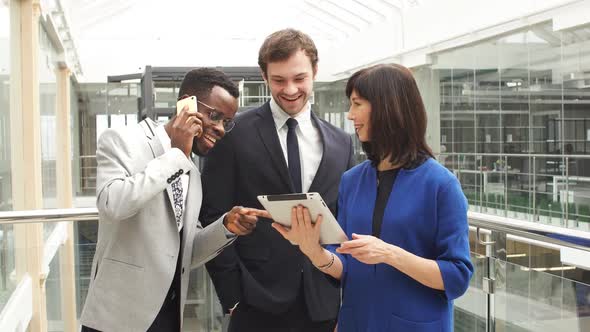 Multi-racial Business People Using Digital Tablet on Meeting in Modern Office Lobby