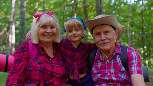 Old Senior Grandparents Couple Tourists Hikers Resting in Forest with Granddaughter in Summer Wood