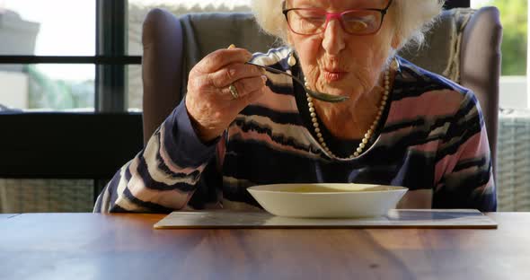 Senior woman having soup on dining table at home 4k