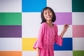 Little girl blushing and expressing happiness in front of a colourful backdrop - PhotoDune Item for Sale