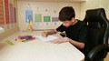 deaf teenager with cochlear implants draws with colored pencils at a desk - PhotoDune Item for Sale