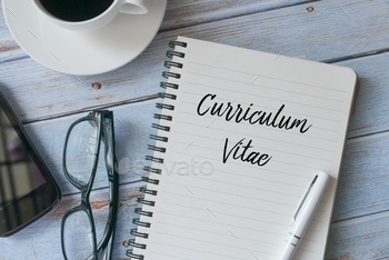en and book written with Curriculum Vitae on wooden background.