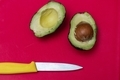 Avocado cut in the middle and yellow knife on red background - PhotoDune Item for Sale