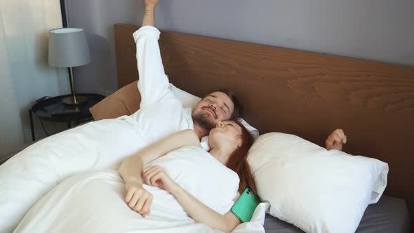 Young Couple Wakes Up Early Sunny Morning in Hotel Room