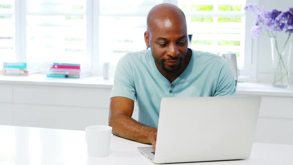 Man using laptop in kitchen 4k