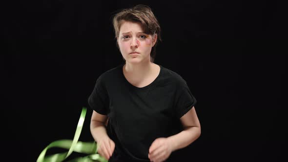 Desperate Woman with Beaten Face Releasing From Gift Ribbon at Black Background