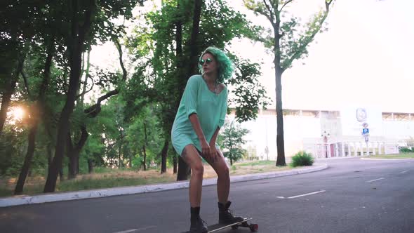 Beautiful Young Girl with Green Hair Riding on Longboard During Sunset Slow Motion Tracking Shot