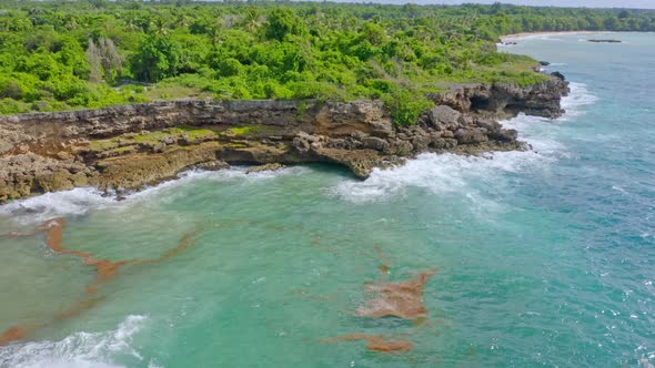 Aerial View of Turquoise Ocean Waves Crash against Rocky Tropical Coastline of Dominican Area of Boc