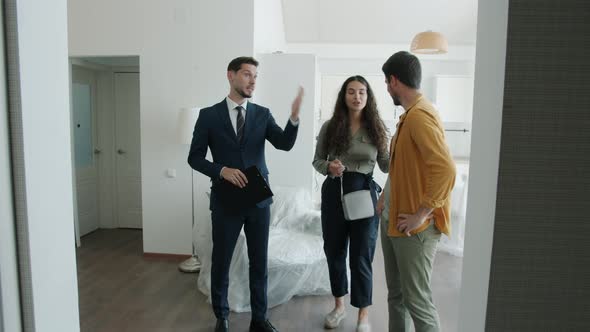 Young Family Man and Woman Looking at New Apartment and Talking to Real Estate Agent