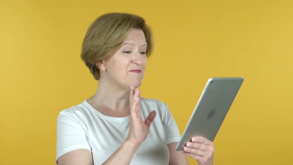 Video Chat By Old Woman Via Tablet Isolated on Yellow Background