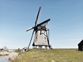 A Dutch windmill in a picturesque countryside on a bright sunny day with blue sky - PhotoDune Item for Sale