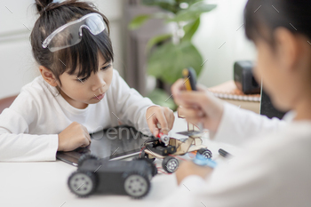 Two Asian students learn coding robot cars and electronic board cables in STEM,