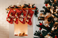 Four Christmas red socks hanging on white fireplace in room. - PhotoDune Item for Sale