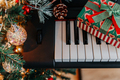 a Christmas gift on piano keys and a decorated Christmas tree with lights - PhotoDune Item for Sale