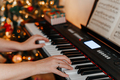 close up of many hands plays on Piano Keys with Christmas tree - PhotoDune Item for Sale