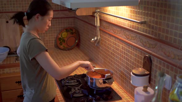 woman preparing marinara sauce from tomatoes in saucepan