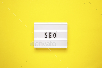 Lightbox with word SEO on yellow background. Search Engine Optimization ranking concept.