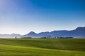 Farm in a field with mountains and blue sky. - PhotoDune Item for Sale