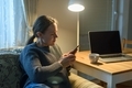 Woman using her phone sitting near laptop - PhotoDune Item for Sale