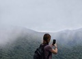 Woman taking a photo of mountains on a foggy morning - PhotoDune Item for Sale