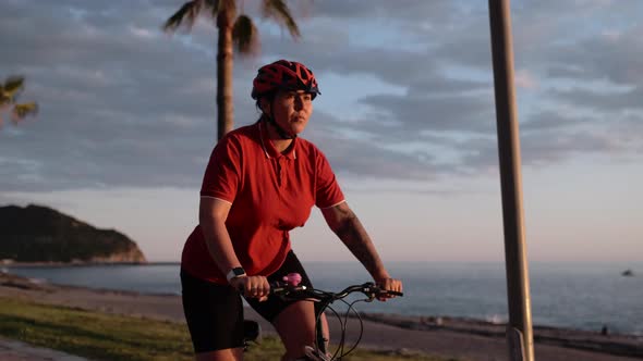 Asian Young Beautiful Woman Riding Bicycle at Evening Sunset in Public Seafront Park