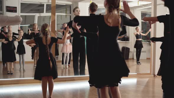 Serious Ballet Teacher Showing Movement To Children in Front of Mirror and Walking Away Talking