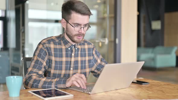 Surprised Young Designer Having Success on Laptop in Modern Office