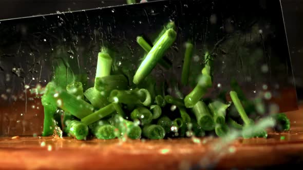 Super Slow Motion Pieces of Green Onion Cut Off with a Large Knife