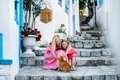 Mom and daughter in pink dresses sitting on the stairs on the street of old city in Marmaris  - PhotoDune Item for Sale