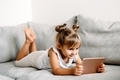 Toddler girl playing with digital wireless tablet computer on couch at home.  - PhotoDune Item for Sale