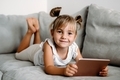 Toddler girl playing with digital wireless tablet computer on couch at home.  - PhotoDune Item for Sale