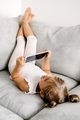 Toddler girl playing with digital wireless tablet computer on couch at home.  - PhotoDune Item for Sale