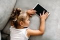 Toddler girl  lies on couch at home and  have rest after playing with digital wireless tablet - PhotoDune Item for Sale