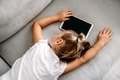 Toddler girl have a rest near digital wireless tablet computer on couch at home.  - PhotoDune Item for Sale