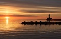 Sunrise over Lake Superior with beautiful orange hues and silhouettes of a lighthouse and rocks  - PhotoDune Item for Sale