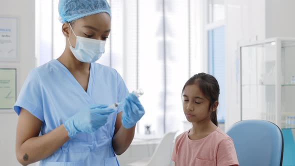 Crop View of Female Medical Nurse in Protective Mask Hat and Safety Gloves Filling Syringe with