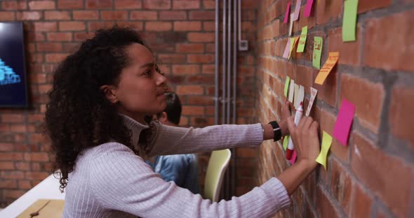 Creative businesswoman writing on sticky notes in modern office