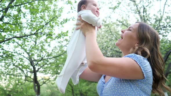 Fair Haired Young Woman in Blue Dress Holds Little Daughter