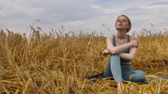 girl has a break during practice yoga in a wheat field
