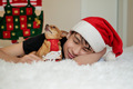 a teenager in a Santa Claus hat sleeps on a bed with a dog in a New Year's tie  - PhotoDune Item for Sale