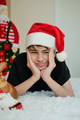 a teenager in a Santa Claus hat lies on a bed against the background of the advent calendar - PhotoDune Item for Sale