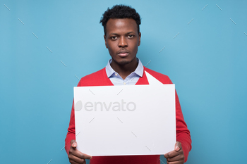 Handsome serious african business man presenting some product on empty placard.
