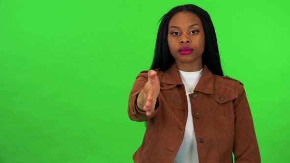 A Young Black Woman Extends Her Arm To the Camera for a Handshake - Green Screen Studio