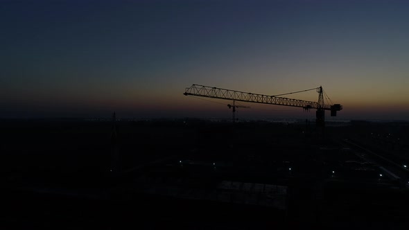 Silhouette of a Construction Crane Against a Sunset or Dawn Background