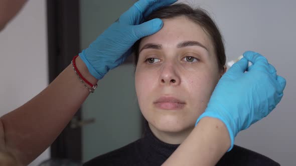 a Young Woman Removes Paint From Freshly Dyed Eyebrows with a Cotton Pad