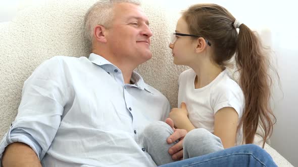 Cute Daughter is Kissing Her Greyhaired Father with Love at Home Father's Day Concept