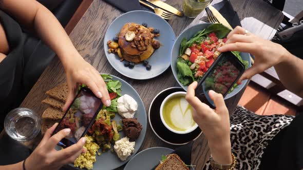 Top View of Hands of Two People Taking Pictures of a Colorful Healthy Brunch 